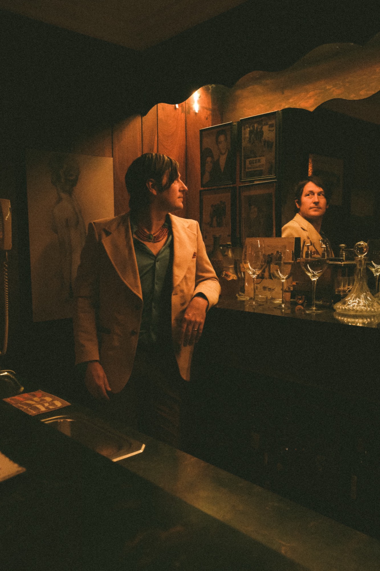 Jonathan Sexton leaning at a wood-paneled bar in warm lamplight, his reflection held in the mirror behind him.
